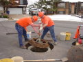 Two workers are shown installing a sewer manhole ring.